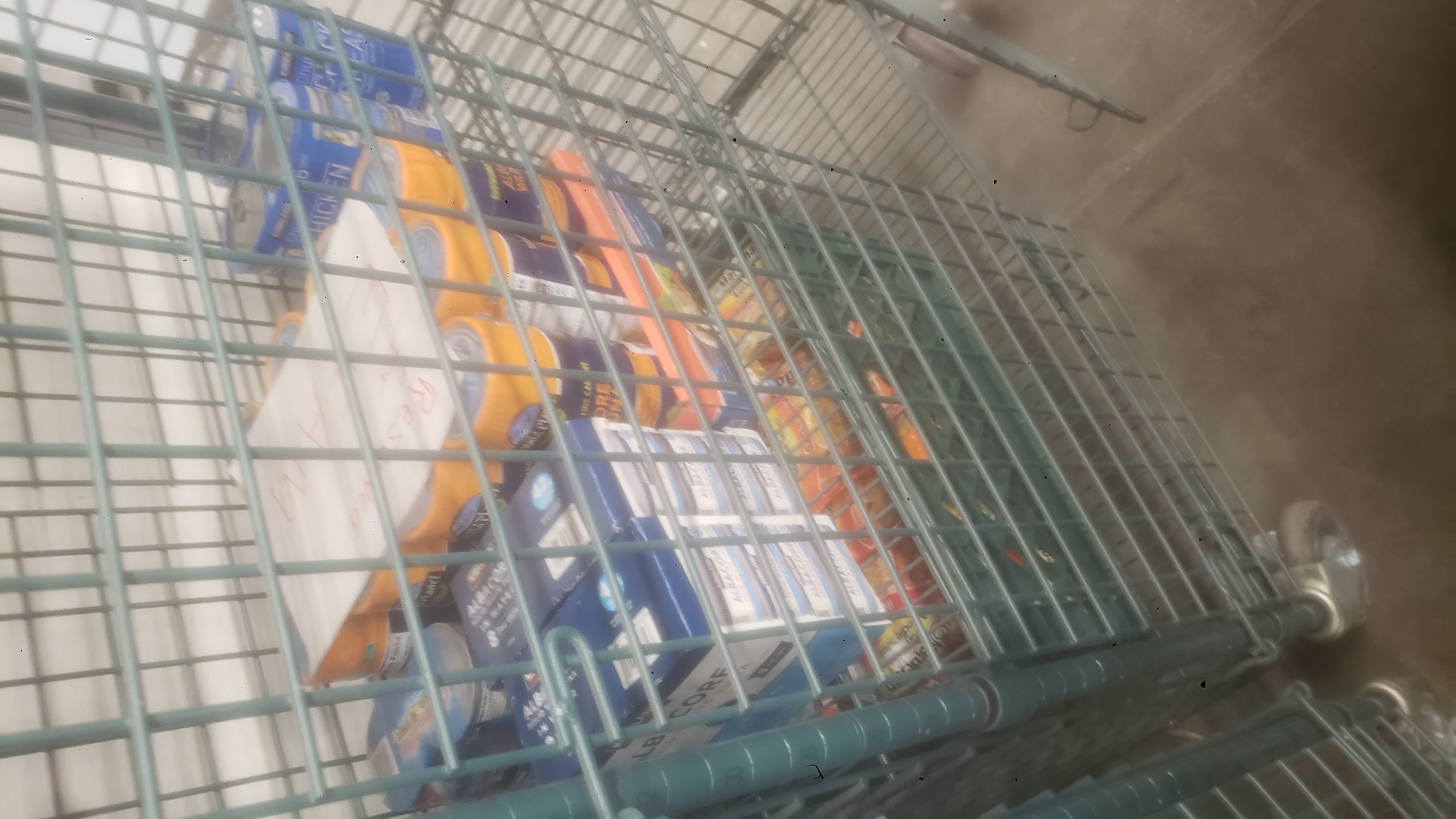 Canned meats and crates of ramen noodles in a cage shelf.